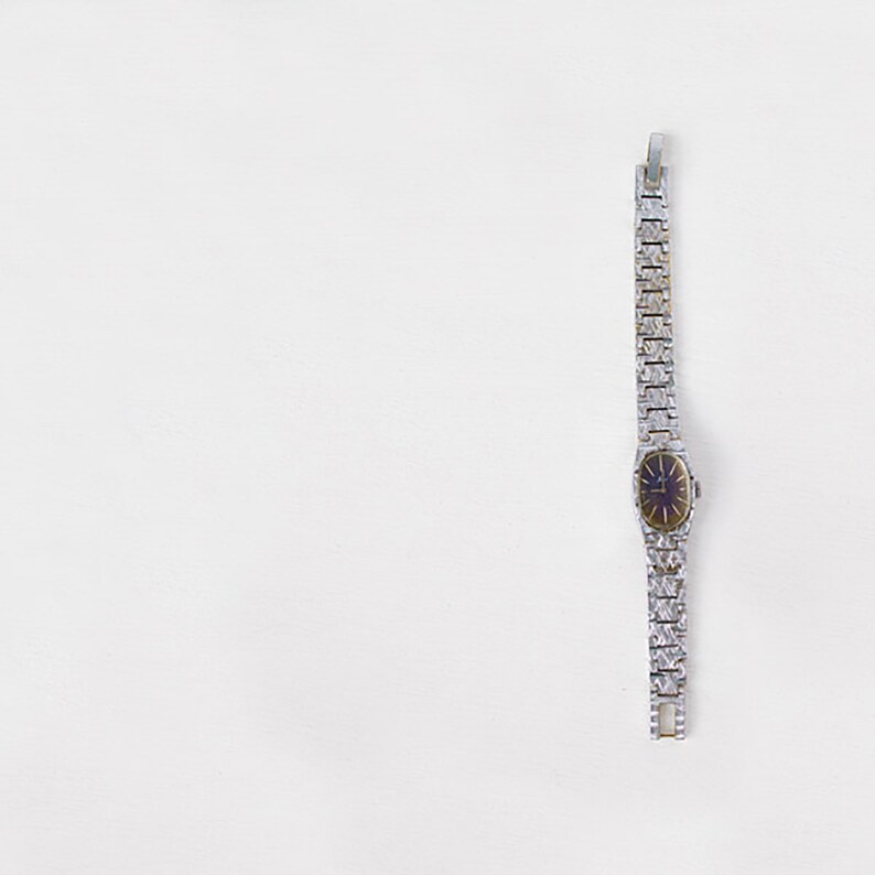 May include: A silver watch with a silver band and a dark blue face.