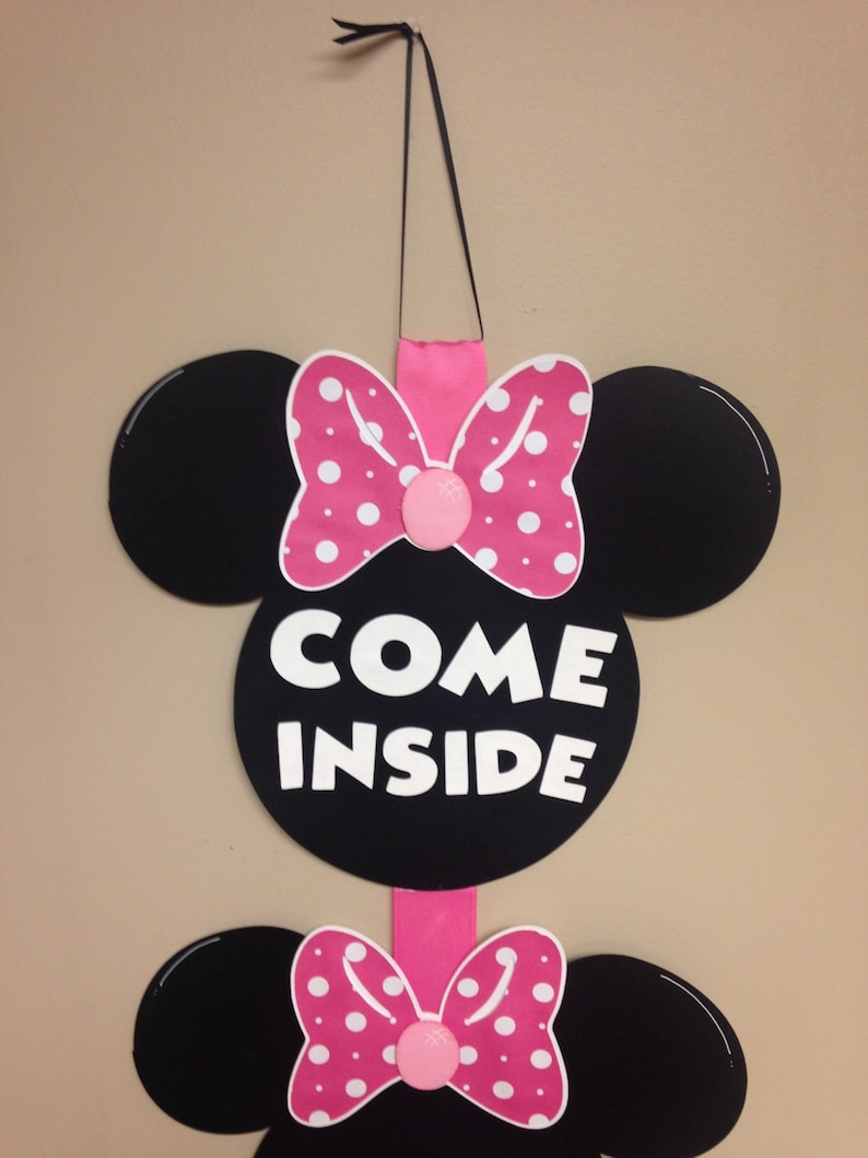 May include: A pink and black Minnie Mouse themed door hanger with the words "Come Inside" in white letters.