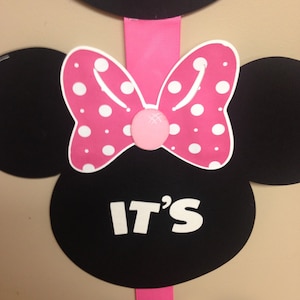 May include: Black and pink Minnie Mouse themed party decoration with the text "IT'S" in white letters.