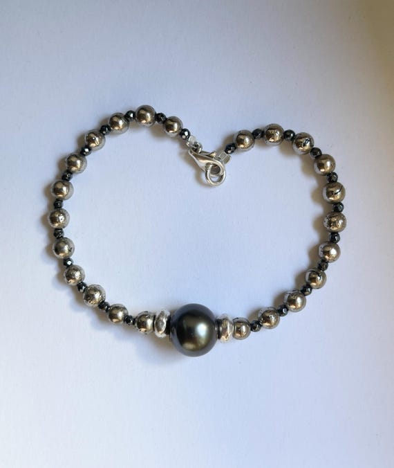 A delicate bracelet featuring a beautiful dark grey Tahitian pearl, pyrites and hematites beads, sterling silver