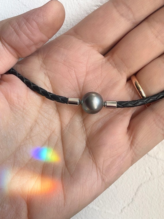 Necklace made with a beautiful semi-round Tahitian pearl on round braided black leather. Steel Clasp, unisex necklace 45,5cm length