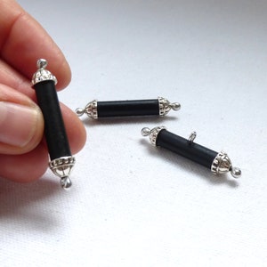 May include: Three black wooden toggle buttons with silver metal accents. The buttons are cylindrical in shape and have a decorative design on the ends.