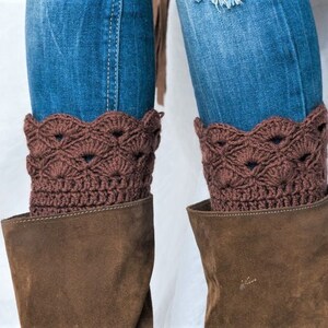 May include: Brown crocheted boot cuffs with a scalloped edge. The cuffs are worn over brown suede boots and blue jeans.
