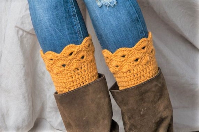 May include: A pair of brown suede boots with yellow crocheted leg warmers. The leg warmers have a scalloped edge and a delicate openwork design.