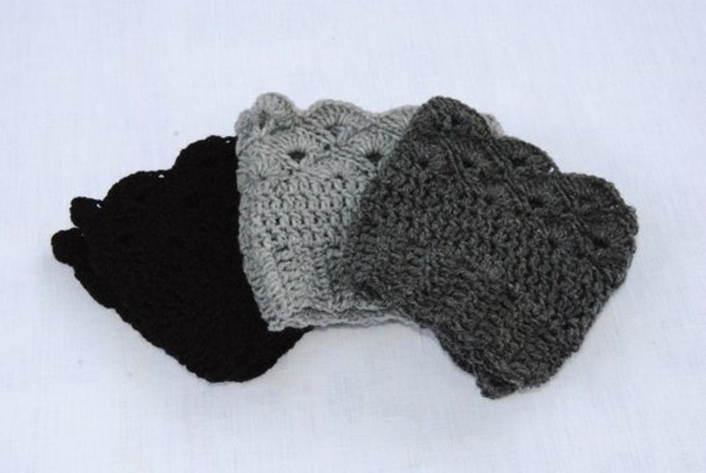 May include: Three crocheted hats in black, grey, and light grey. The hats are made with a textured stitch and have a scalloped edge.