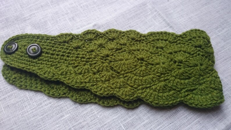 Peut inclure: Un chauffe-cou crochet&eacute; vert avec deux boutons noirs.