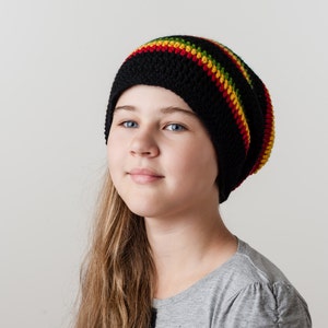 Op de afbeelding: Een jong persoon met lang bruin haar dat een zwarte en rode gestreepte gebreide muts draagt.