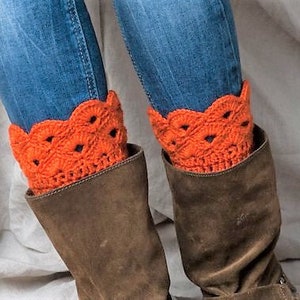 May include: A pair of brown leather boots with orange crocheted leg warmers. The leg warmers have a scalloped edge and a delicate openwork design.