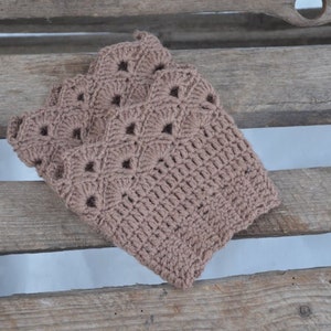 May include: A brown crocheted leg warmer with a lacy pattern.