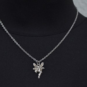 Peut inclure: Un collier en cha&icirc;ne argent&eacute;e avec un pendentif en forme de f&eacute;e. La f&eacute;e est repr&eacute;sent&eacute;e avec des ailes et une robe flottante.