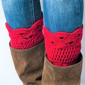 May include: Red crocheted boot cuffs with a lacy design. The cuffs are worn over brown boots and blue jeans.