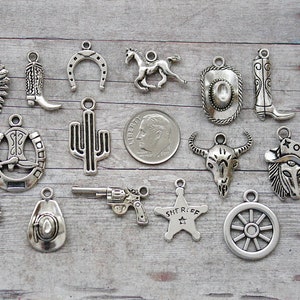 May include: A collection of 18 silver-toned metal charms with western and cowboy themes. The charms include a horseshoe, cactus, cowboy boot, cowboy hat, sheriff's star, and more.