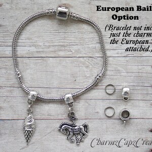 K&ouml;nnte beinhalten: Zwei silberne Charms mit europ&auml;ischen &Ouml;senbefestigungen. Ein Charm ist ein silberner Eiswaffel und der andere ein silbernes Karussellpferd. Der Text "European Bail Option" und "(Bracelet not included- just the charms with the European Bails attached.)" ist im Bild sichtbar.