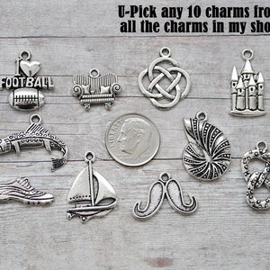 May include: A collection of silver-toned charms, including a football, couch, Celtic knot, castle, fish, sneaker, sailboat, mustache, seashell, and pretzel. The text "U-Pick any 10 charms from all the charms in my shop" is visible.