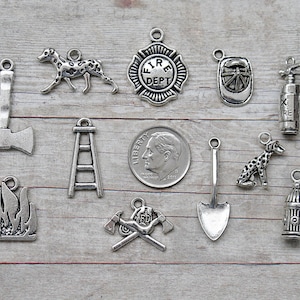 May include: A collection of silver-toned metal charms with firefighter themes. The charms include a fire hydrant, a ladder, a Dalmatian dog, a fire extinguisher, a fireman's helmet, a fire axe, a shovel, a fire department badge, and a fire truck.