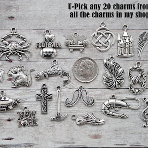 May include: A collection of silver-toned charms, including a crab, football, sofa, knot, castle, wings, pumpkin, squirrel, fish, shell, pretzel, moon, submarine, cross, mustache, hammer, shoe, shrimp, and musical note. Text reads: "U-Pick any 20 charms from all the charms in my shop."