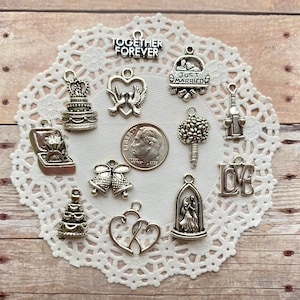 May include: Assortment of silver charm pendants with wedding themes, including a cake, a ring, a heart with doves, a bouquet, a bell, a couple dancing, a car with "Just Married" written on it, a bottle of wine, and the words "Together Forever" and "Love".