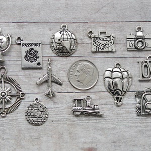 May include: A collection of 12 silver charm pendants with travel themes, including a globe, compass, airplane, hot air balloon, suitcase, camera, passport, train, and the word "LOVE".