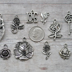 May include: A collection of silver-toned metal charms featuring roses, keys, and the word "LOVE".