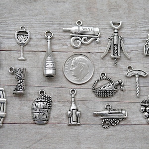 May include: A collection of 14 silver-toned metal charms with wine-themed designs, including grapes, wine bottles, wine glasses, a wine barrel, a corkscrew, and a wine basket. The charms are perfect for jewelry making, scrapbooking, or other craft projects.