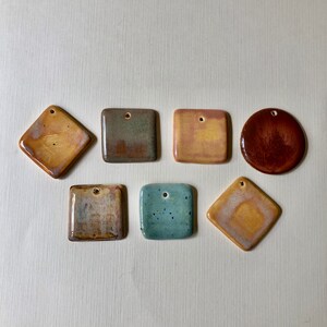 May include: Seven ceramic tiles in various colors and patterns. The tiles are square and have a hole in the center. The colors include brown, green, blue, yellow, and orange.