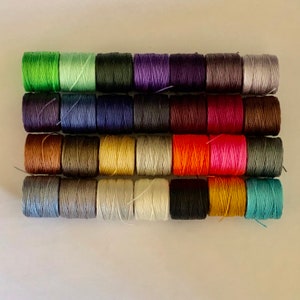 以下が含まれることがあります： 緑、青、茶色、赤、オレンジ、黄色、白、灰色、黒など、さまざまな色の糸が24個巻かれた糸巻きです。