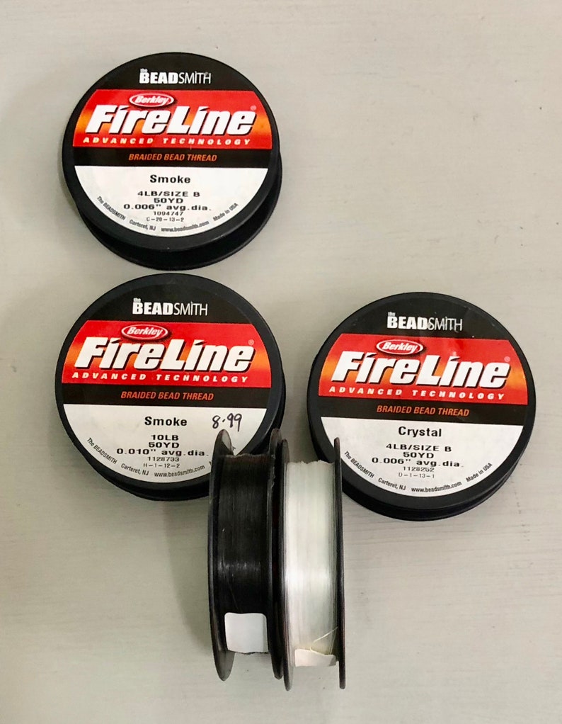 May include: Three spools of Berkley FireLine braided bead thread. The spools are labeled with the thread type, size, and color. The colors are Smoke, Smoke, and Crystal. The thread is 4lb and 50 yards.