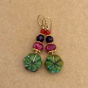 May include: A pair of dangle earrings with green, pink, purple, and orange gemstone beads. The earrings have gold wire and a gold hook.