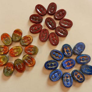 May include: Three groups of oval-shaped glass tiles with different patterns. The first group is red, orange, and yellow. The second group is blue, green, and yellow. The third group is blue and white.