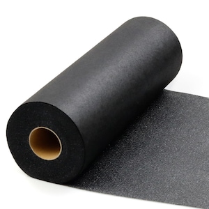 May include: A roll of black fabric with a textured surface. The fabric is rolled around a cardboard core, with a portion unrolled, revealing the texture. The material appears to be a non-woven fabric.