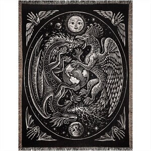 May include: Black and white woven tapestry featuring a dragon and a phoenix facing each other. The mythical creatures are surrounded by a circle of stars and a sun with a human face. The tapestry has a textured, woven look.