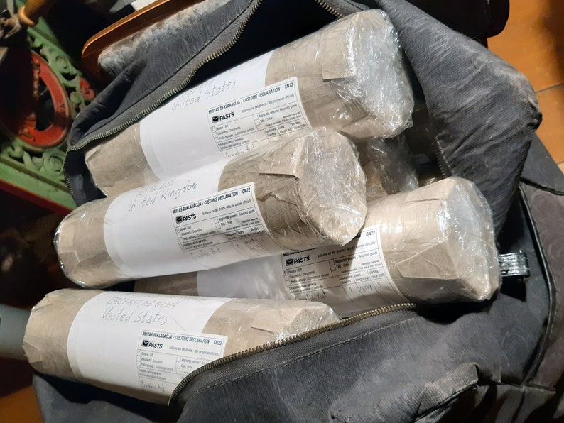 May include: A black bag filled with several brown paper-wrapped packages. Each package has a white label with the text "United States" and "United Kingdom" and a "PASTS" logo.