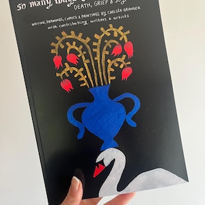 May include: A book titled "So Many Ways to Draw a Ghost" with the subtitle "Death, Grief & Joy." The cover is black with a blue vase, gold floral design, red flowers, and a white swan. The book is about writing, drawings, comics, and paintings.