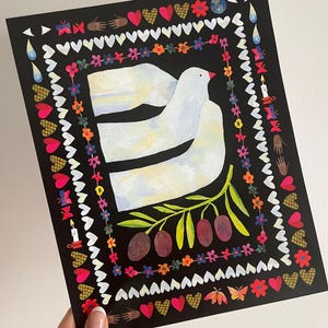 May include: A rectangular art print on a black background featuring a central white dove in flight above an olive branch with three dark olives. The image is framed by a colorful border of small flowers, hearts, butterflies, candles, and hands.