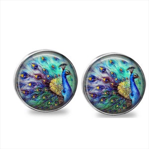 May include: Two round, silver-toned stud earrings. Each earring features a vibrant peacock design with blue, green, yellow, and purple feathers. The peacock's body is a mix of blue and gold, set against a light blue background.