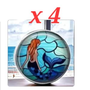 May include: A round, silver-toned pendant featuring a mermaid design. The mermaid has red hair and a blue tail, set against a stained-glass style background of blues and greens. The text "X 4" is in red at the top.