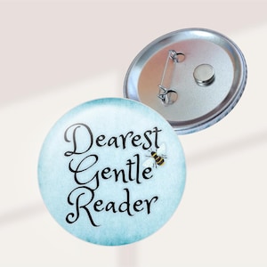 May include: A round button with the text "Dearest Gentle Reader" in black script on a light blue background. A small bee graphic is on the right side. The back of the button is silver.