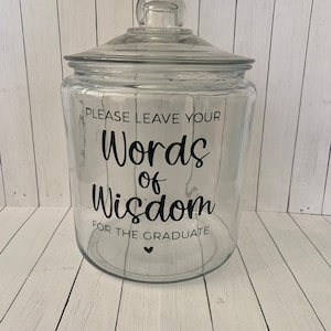 Könnte beinhalten: Ein klares Glasgefäß mit Deckel, verziert mit schwarzer Schrift, die "Bitte hinterlassen Sie Ihre Worte der Weisheit für den Absolventen" lautet.