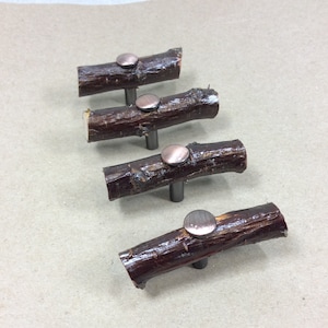 May include: Four wooden cabinet knobs with a rustic brown finish and silver metal accents. Each knob is shaped like a small log with a round metal piece on top.