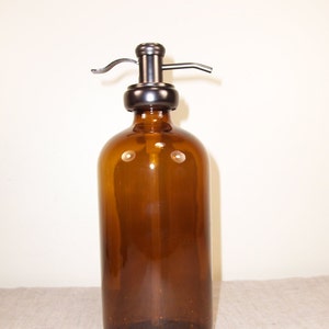 May include: A brown glass bottle with a metal pump dispenser. The bottle is empty and ready to be filled with soap or lotion.