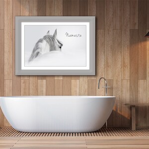 Pu&ograve; includere: Una fotografia in bianco e nero di una testa e un collo di cavallo, con la parola "Namaste" stampata sotto. La foto &egrave; incorniciata in una cornice grigia e appesa a un muro di legno sopra una vasca da bagno bianca.
