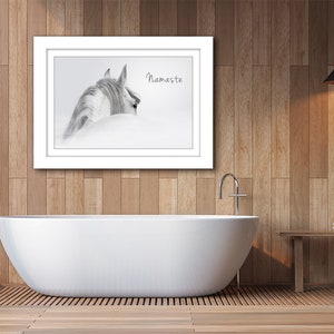 Pu&ograve; includere: Una fotografia in bianco e nero di una testa e un collo di cavallo, con il testo "Namaste" stampato sull'immagine. La foto &egrave; incorniciata e appesa a un muro in un bagno con una vasca da bagno bianca e pannelli di legno.