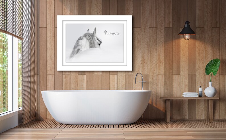 Pu&ograve; includere: Una fotografia in bianco e nero di una testa e un collo di cavallo, con il testo "Namaste" stampato sull'immagine. La foto &egrave; incorniciata e appesa a un muro in un bagno con una vasca da bagno bianca e pannelli di legno.