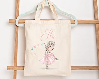 May include: Cream-colored tote bag featuring a ballerina illustration in a pink tutu and bow. The name "Ella" is written in cursive above the ballerina. The ballerina is holding a string of colorful flags.