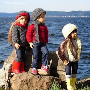 May include: Three dolls wearing winter clothing stand on rocks by a body of water. The doll on the left is wearing a gray knitted sweater, a red knit hat, and red rain boots. The doll in the middle is wearing a red knitted sweater, a gray knit hat, and red sneakers. The doll on the right is wearing a gray sweater, a yellow knit hat, and yellow rain boots.