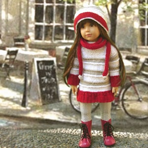 Könnte beinhalten: Eine Puppe trägt einen weiß-rot gestreiften Pullover mit einer weißen Strickmütze und einem roten Schal. Die Puppe trägt weiße Strumpfhosen und rote Stiefel. Die Puppe steht vor einem Gebäude mit einem Schild, auf dem "Green in the.