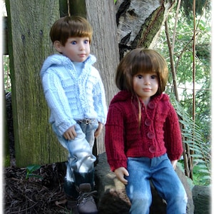 May include: Two dolls wearing sweaters and jeans. The doll on the left is wearing a light blue sweater and the doll on the right is wearing a red sweater.