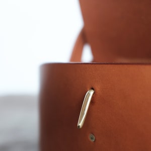 May include: A brown leather box with a gold metal latch. The box is open and the inside is visible.