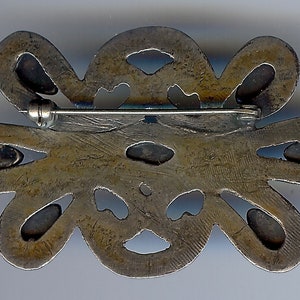 May include: Silver tone brooch with a floral design. The brooch has a pin and catch closure on the back.