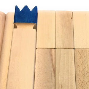 May include: A set of wooden blocks with a blue crown on top. The blocks are arranged in a row, with the crown on the leftmost block.